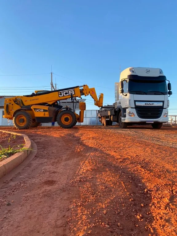 Equipamento de construção junto a caminhão de transporte
